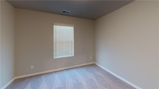 carpeted empty room featuring baseboards and visible vents