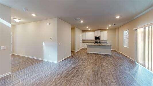 kitchen featuring dark wood finished floors, stainless steel microwave, open floor plan, and white cabinetry