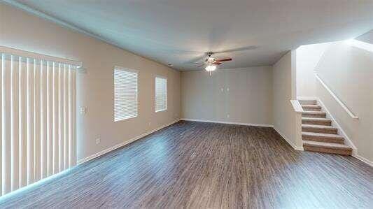 unfurnished room featuring baseboards, stairs, a ceiling fan, and wood finished floors