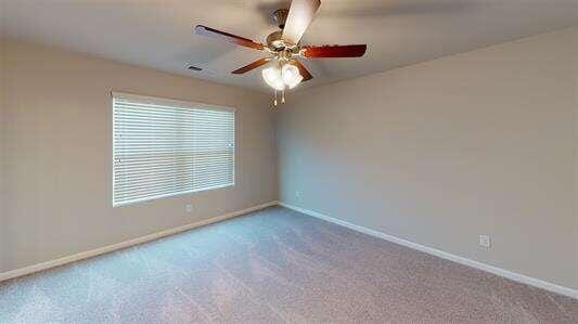 carpeted empty room featuring a ceiling fan and baseboards