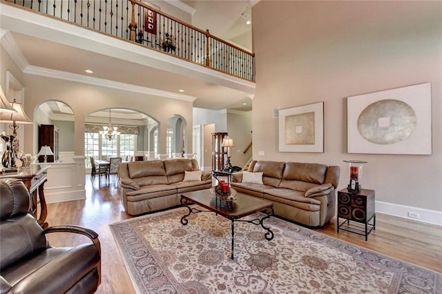 4478 Longmead Rd, Flowery Branch, GA 30542 - living room with ornamental molding, arched walkways, wood finished floors, a chandelier, and a high ceiling