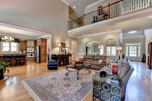 4478 Longmead Rd, Flowery Branch, GA 30542 - living area featuring a chandelier, plenty of natural light, arched walkways, a towering ceiling, and light wood-type flooring