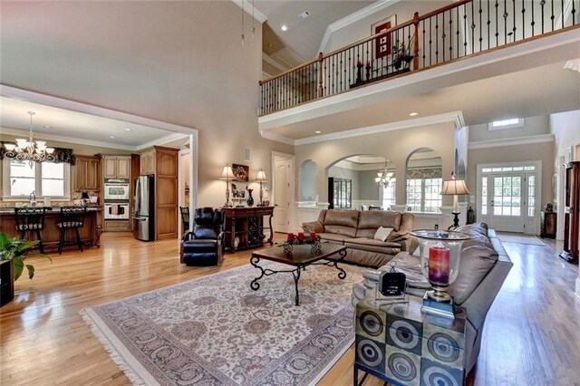 4478 Longmead Rd, Flowery Branch, GA 30542 - living room featuring a chandelier, plenty of natural light, arched walkways, a high ceiling, and light wood-style flooring