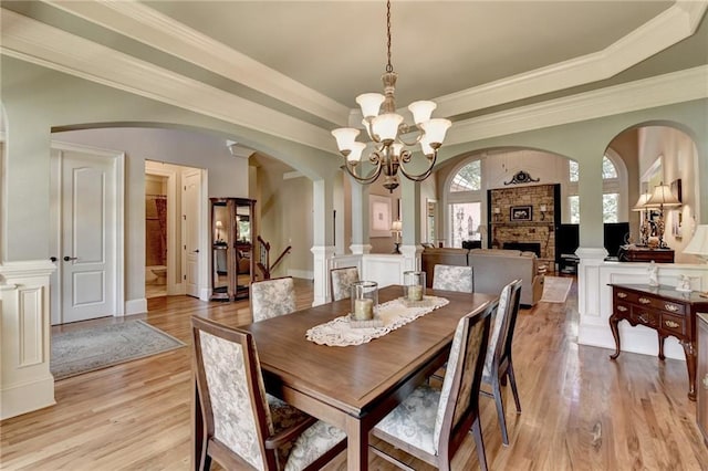 4478 Longmead Rd, Flowery Branch, GA 30542 - dining area featuring arched walkways, light wood-style floors, a chandelier, a stone fireplace, and a raised ceiling