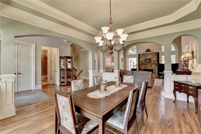 4478 Longmead Rd, Flowery Branch, GA 30542 - dining area featuring arched walkways, light wood-type flooring, a chandelier, a fireplace, and a tray ceiling