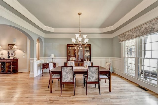 4478 Longmead Rd, Flowery Branch, GA 30542 - dining space featuring arched walkways, a raised ceiling, a chandelier, light wood-type flooring, and crown molding