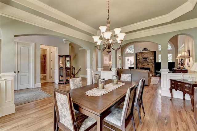 4478 Longmead Rd, Flowery Branch, GA 30542 - dining area featuring arched walkways, light wood-style floors, a chandelier, a stone fireplace, and ornamental molding
