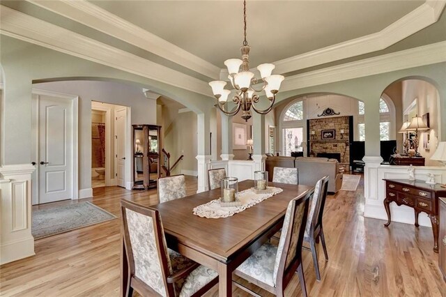 4478 Longmead Rd, Flowery Branch, GA 30542 - dining area with arched walkways, light wood-type flooring, a chandelier, a stone fireplace, and crown molding