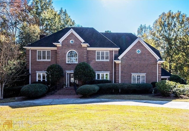 colonial inspired home with a front yard and brick siding