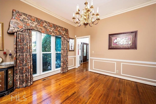 unfurnished dining area with visible vents, crown molding, an inviting chandelier, and wood finished floors