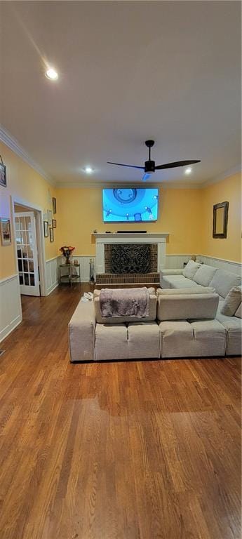 living room with ornamental molding, wood finished floors, and wainscoting