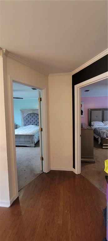 hall with baseboards, wood finished floors, and crown molding