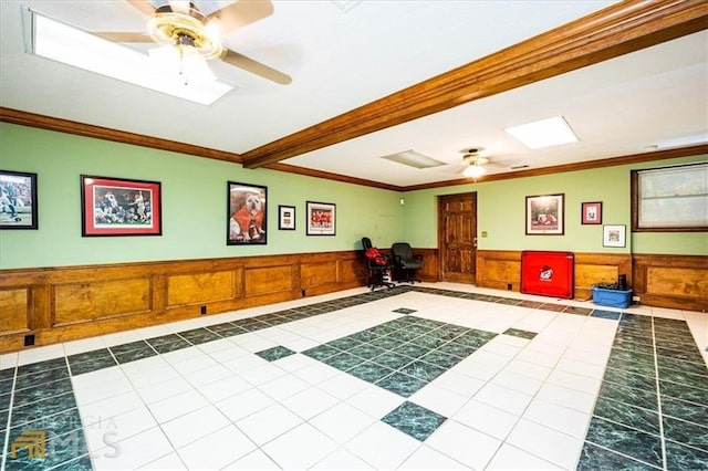 workout area with tile patterned floors, a wainscoted wall, ceiling fan, and crown molding