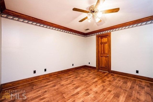 empty room featuring ornamental molding, a ceiling fan, baseboards, and wood finished floors