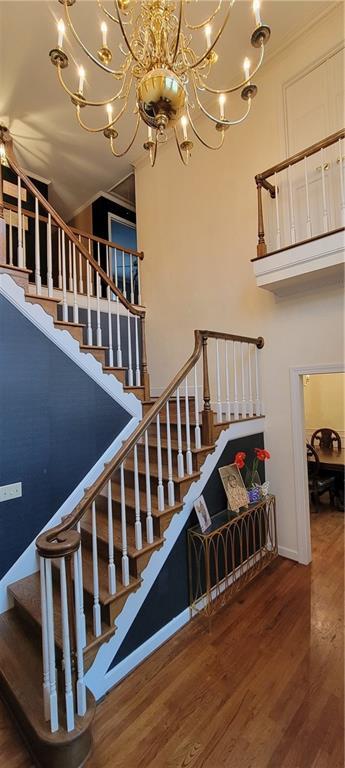 stairway with a notable chandelier, a high ceiling, and wood finished floors