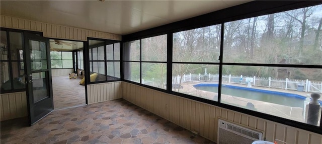 unfurnished sunroom featuring an AC wall unit and ceiling fan