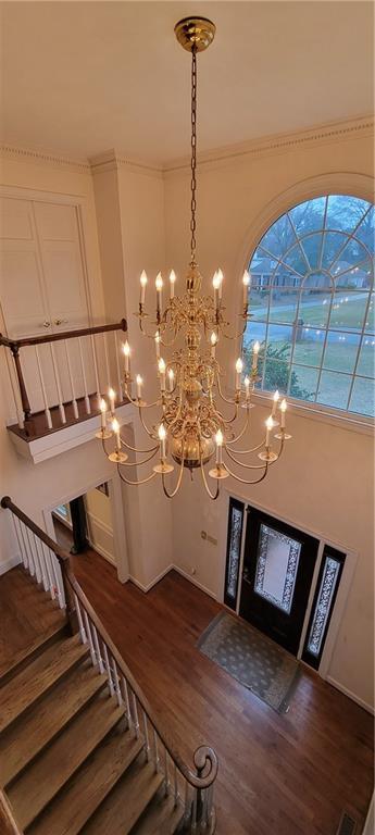 foyer entrance with an inviting chandelier, stairway, dark wood-style floors, and baseboards