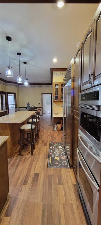 kitchen with decorative light fixtures, light wood-style flooring, appliances with stainless steel finishes, and light countertops