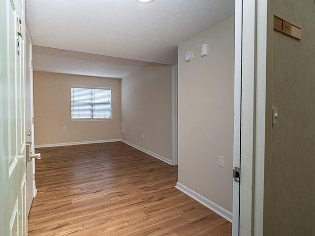 unfurnished room featuring a textured ceiling and light hardwood / wood-style floors