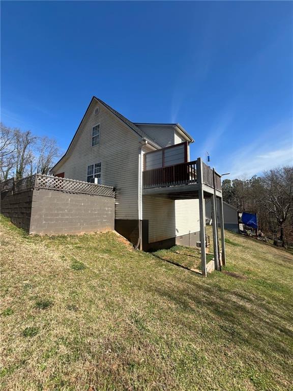 view of side of property with crawl space, a deck, and a yard