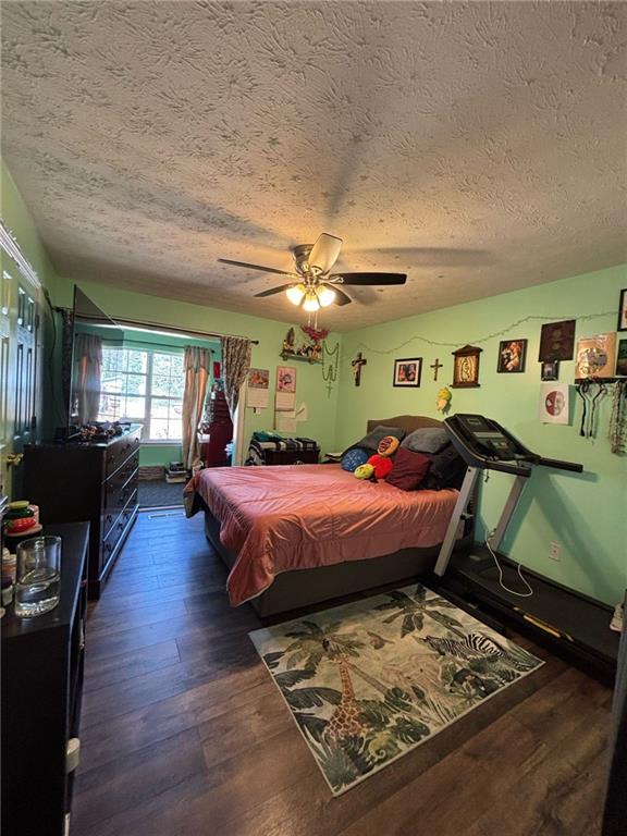 bedroom featuring a textured ceiling, hardwood / wood-style floors, and a ceiling fan