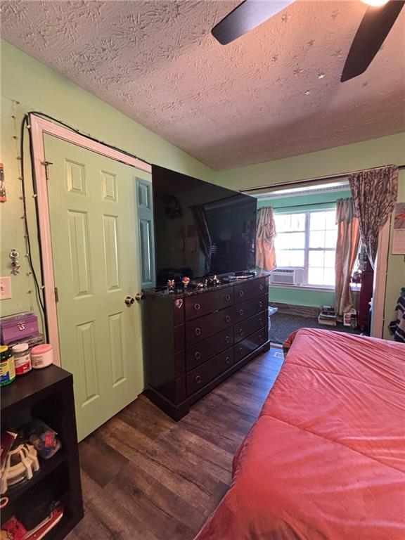 bedroom featuring a textured ceiling, a ceiling fan, and dark wood-style flooring