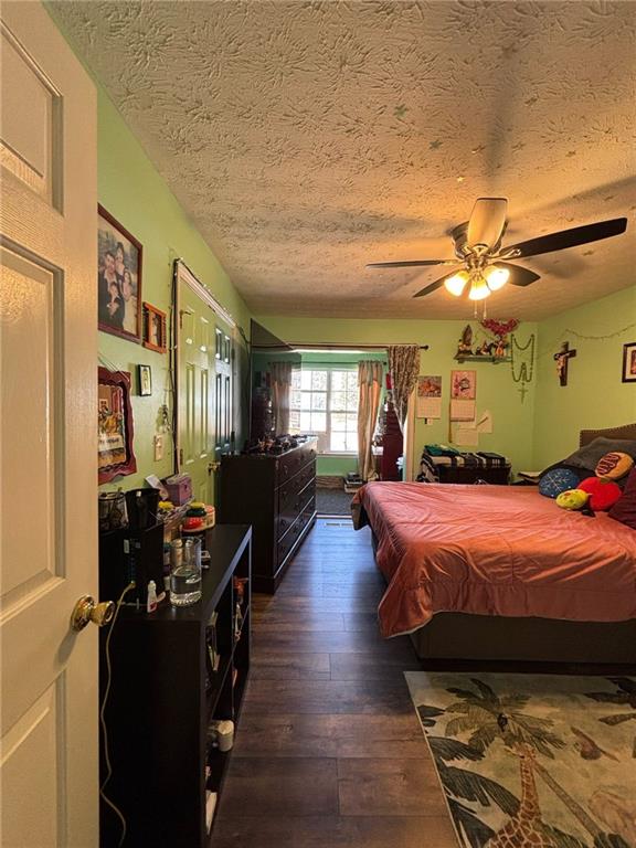 bedroom featuring a textured ceiling, wood-type flooring, and a ceiling fan