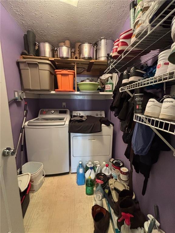 washroom featuring laundry area, washer and clothes dryer, and a textured ceiling