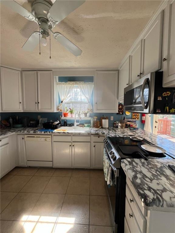 kitchen featuring stainless steel appliances, light tile patterned flooring, a sink, and a textured ceiling