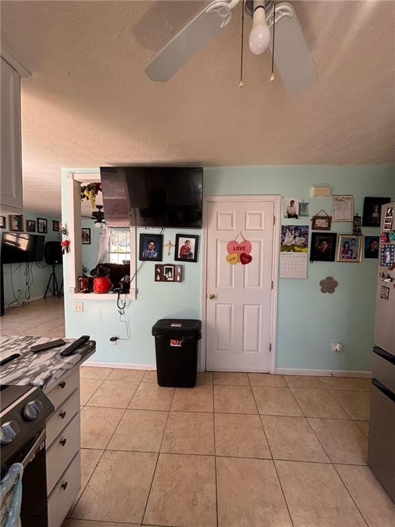 kitchen featuring ceiling fan, freestanding refrigerator, black electric range oven, and light tile patterned flooring