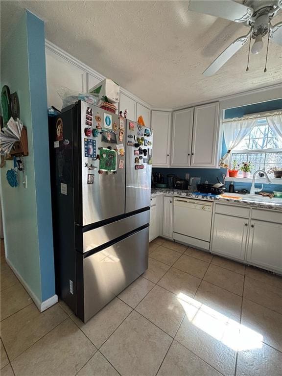 kitchen with freestanding refrigerator, white cabinets, light tile patterned flooring, white dishwasher, and a textured ceiling