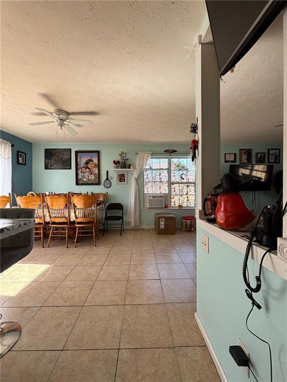 dining space featuring light tile patterned floors, ceiling fan, cooling unit, and a textured ceiling