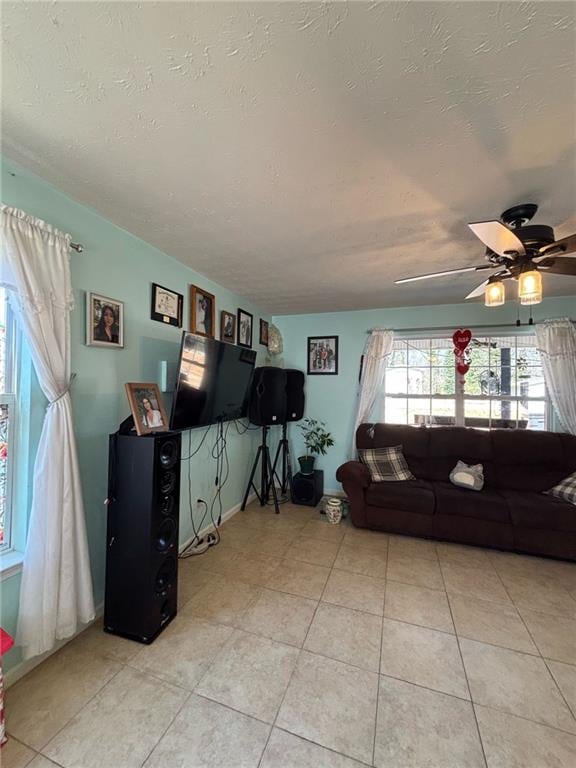 living area with a textured ceiling, ceiling fan, and light tile patterned floors