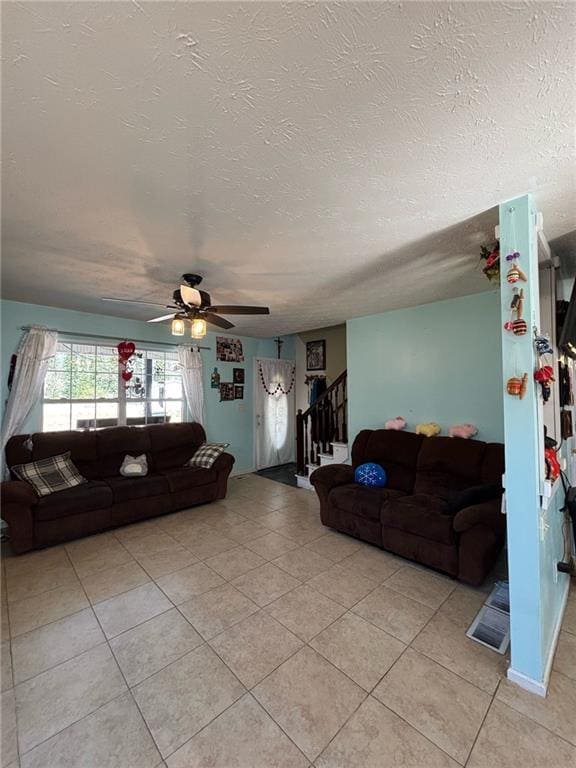 living room with stairs, a textured ceiling, light tile patterned flooring, and a ceiling fan