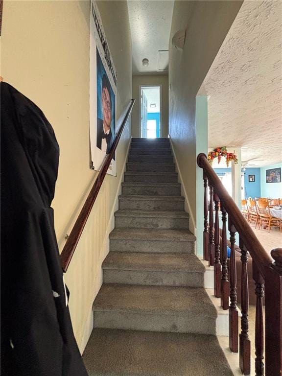 stairs with a textured ceiling and carpet