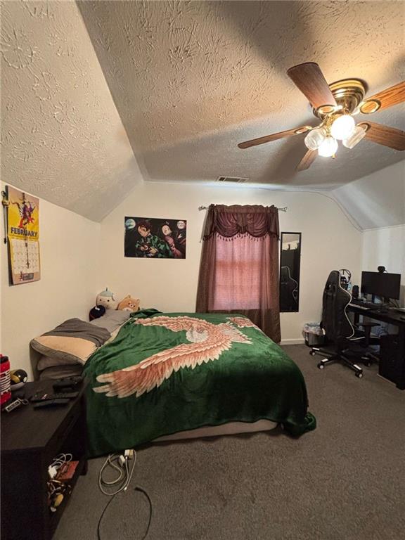 carpeted bedroom featuring a textured ceiling, visible vents, vaulted ceiling, and a ceiling fan