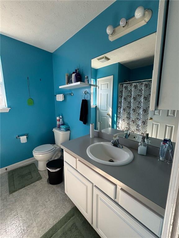 full bathroom featuring baseboards, visible vents, toilet, a textured ceiling, and vanity