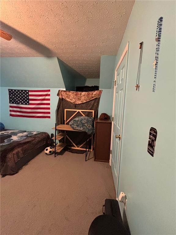 bedroom featuring a textured ceiling, carpet, and a ceiling fan