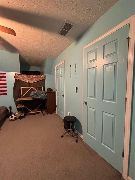 bedroom with carpet floors, visible vents, a textured ceiling, and a ceiling fan