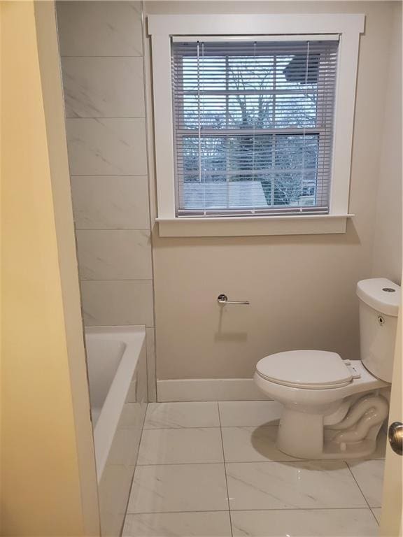 bathroom featuring a tub to relax in and toilet