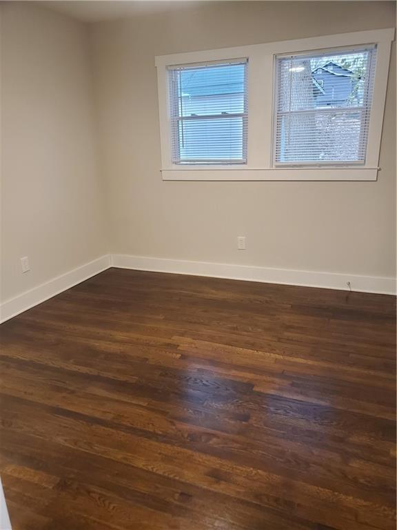 empty room with plenty of natural light and dark hardwood / wood-style floors