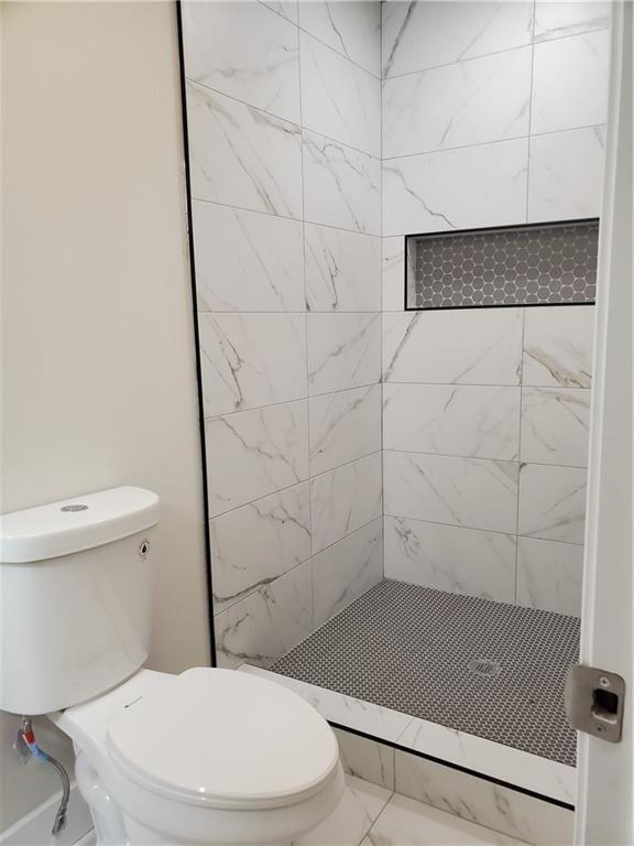 bathroom with tiled shower and toilet