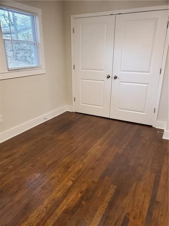 unfurnished bedroom with dark hardwood / wood-style floors and a closet