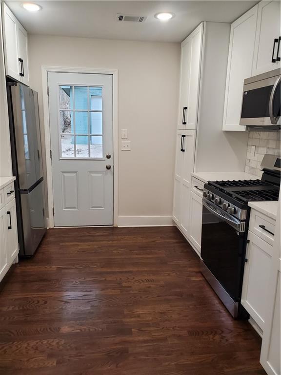 kitchen featuring tasteful backsplash, stainless steel appliances, dark hardwood / wood-style floors, and white cabinets