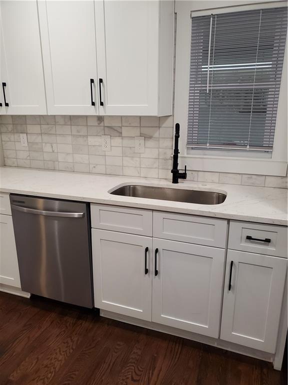 kitchen with sink, tasteful backsplash, white cabinets, dark hardwood / wood-style flooring, and stainless steel dishwasher