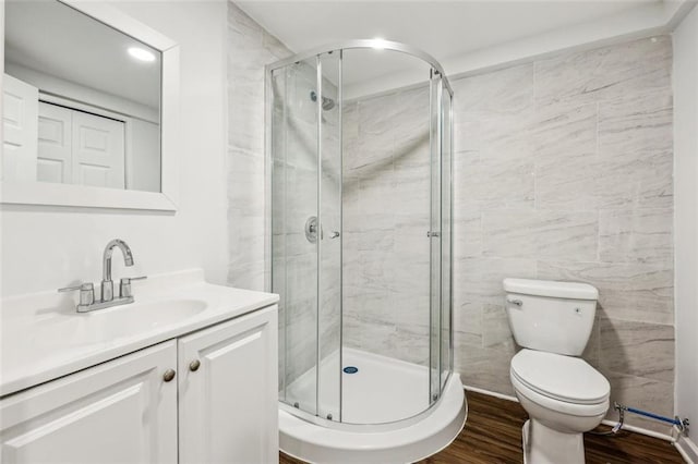 bathroom with vanity, hardwood / wood-style floors, a shower with door, and toilet