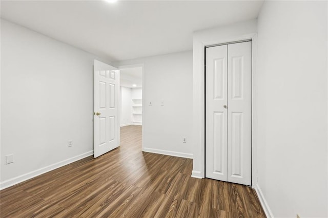 unfurnished bedroom with dark wood-type flooring and a closet