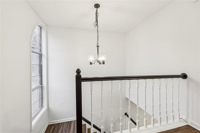 stairs with hardwood / wood-style floors and a chandelier