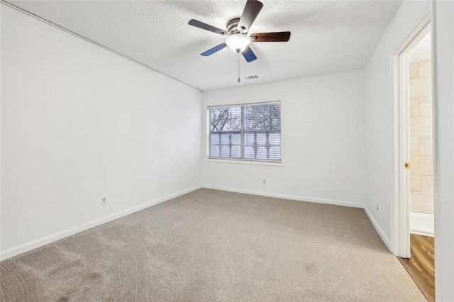 carpeted empty room with ceiling fan and a textured ceiling