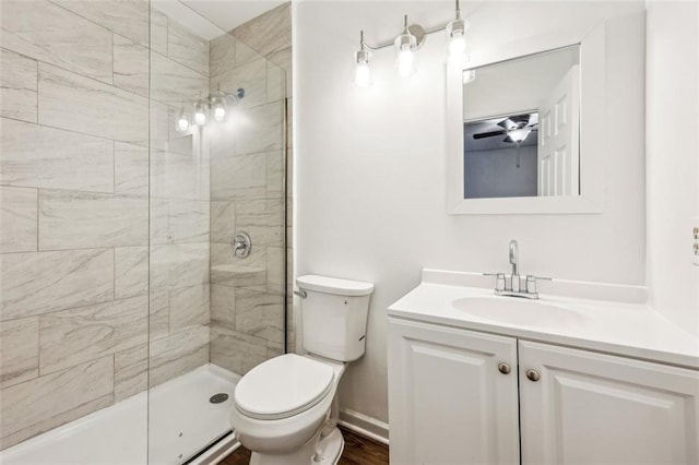 bathroom featuring vanity, ceiling fan, toilet, and tiled shower